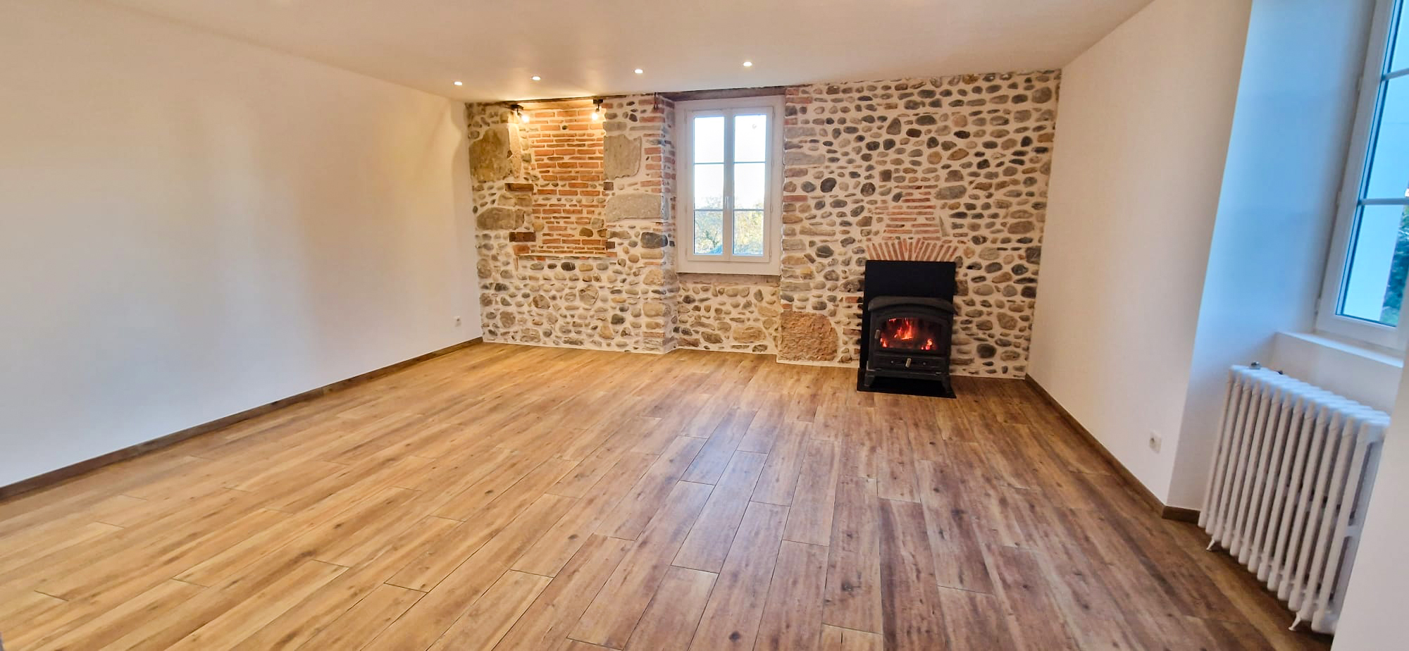 Salon rénové avec carrelage effet bois et mur en pierre à Pau