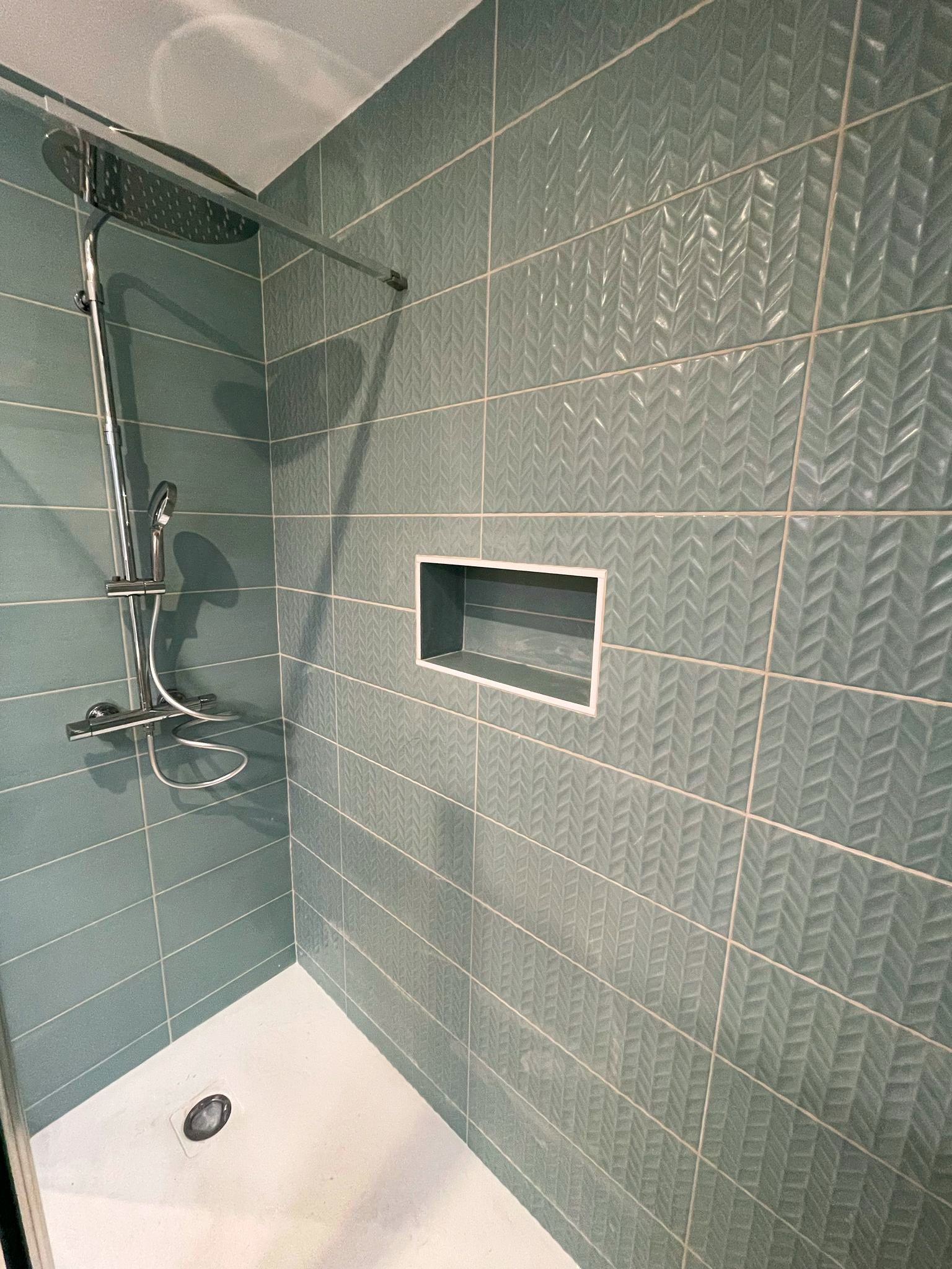 Salle de bain avec carrelage mural vert structuré et robinetterie chromée
