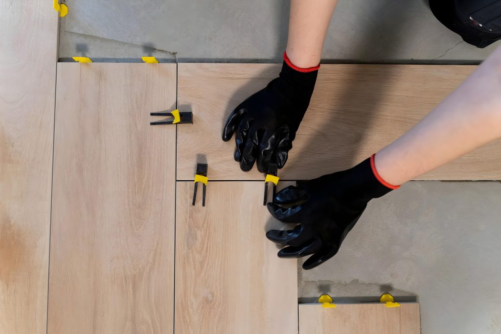 Carreleur en train de poser du carrelage effet bois avec précision